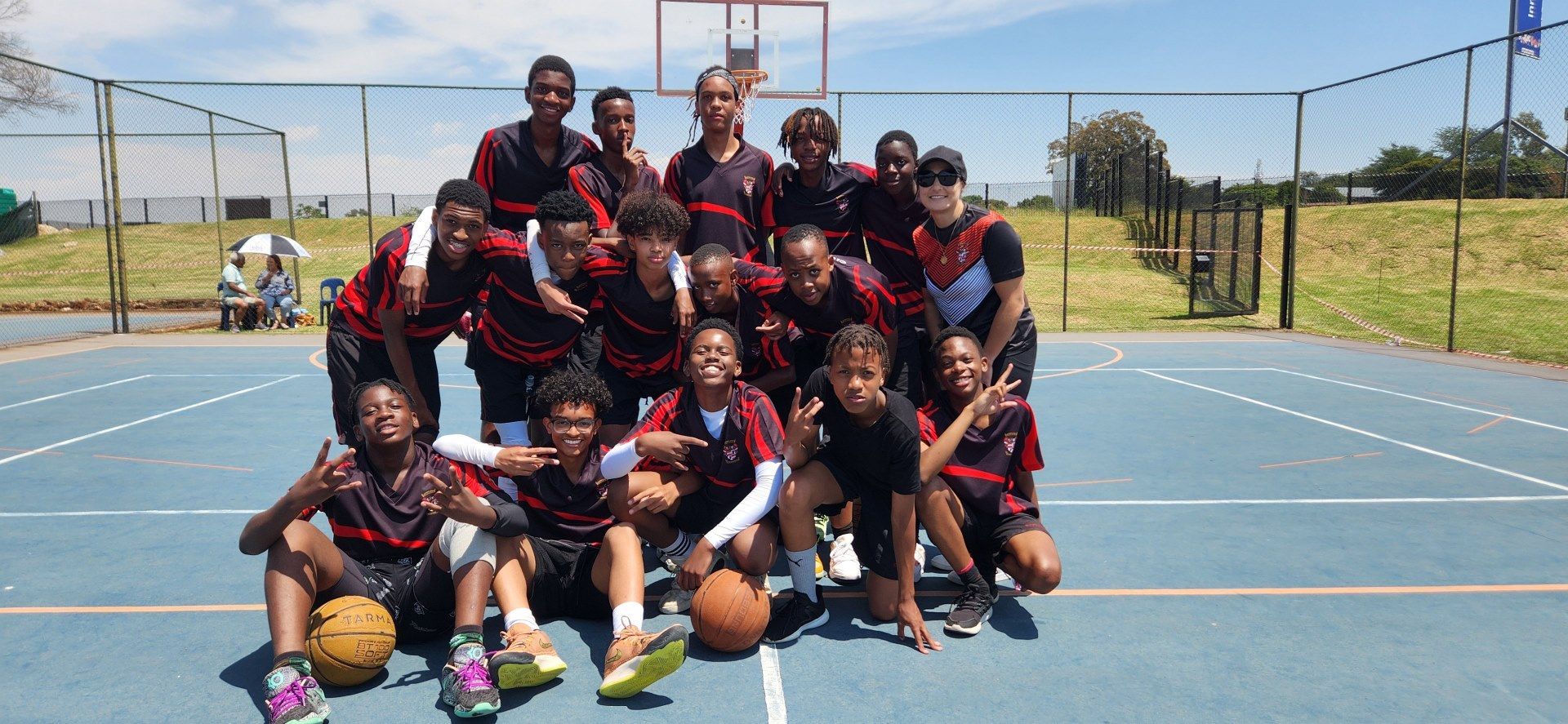 A group of people are posing for a picture on a basketball court.