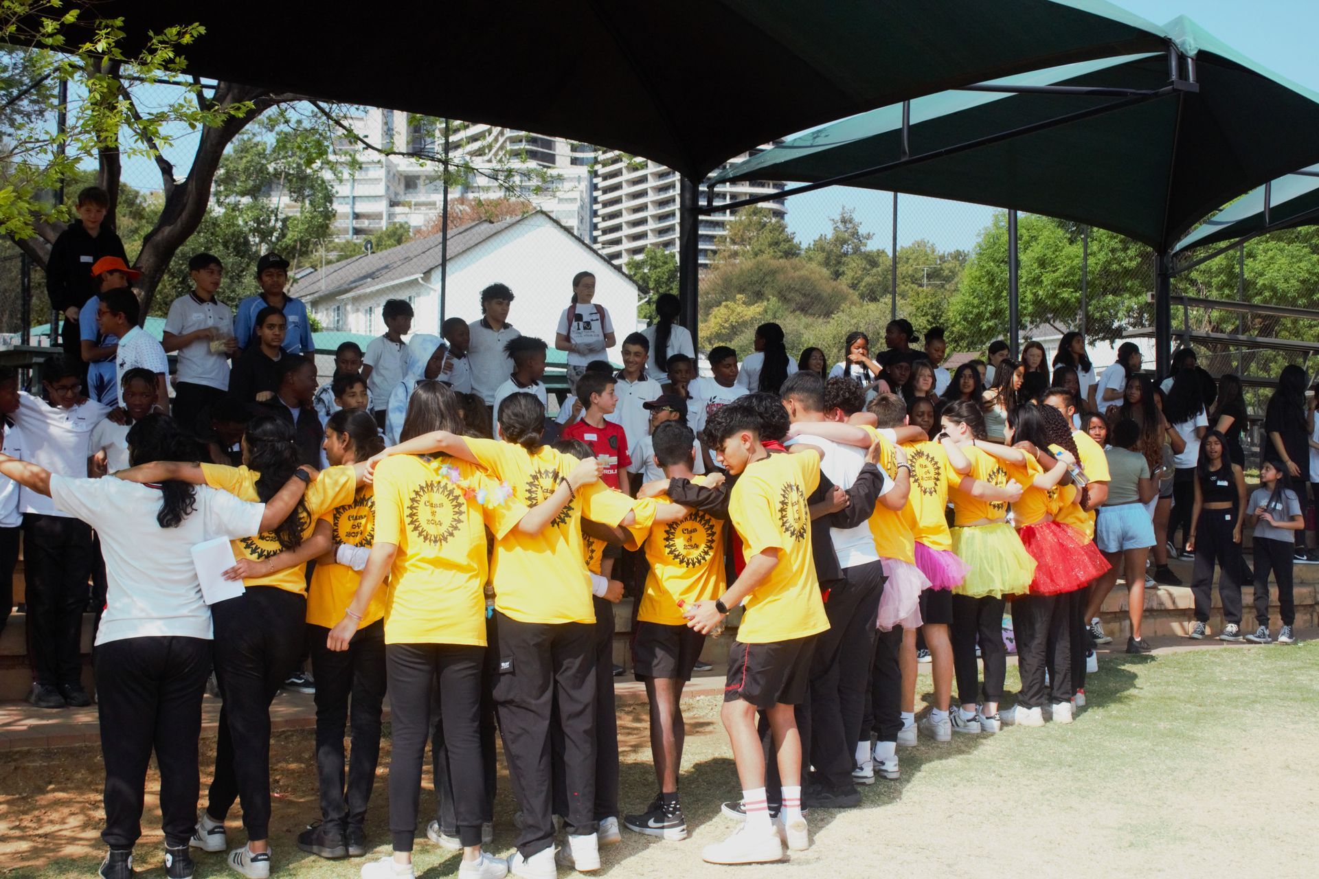 A group of people are standing in a circle with their arms around each other.