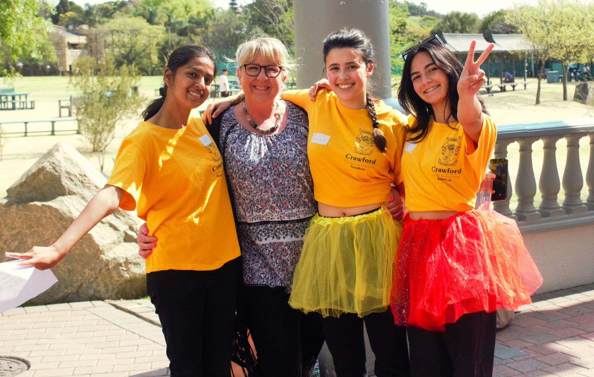 A group of women wearing yellow shirts and tutus are posing for a picture.