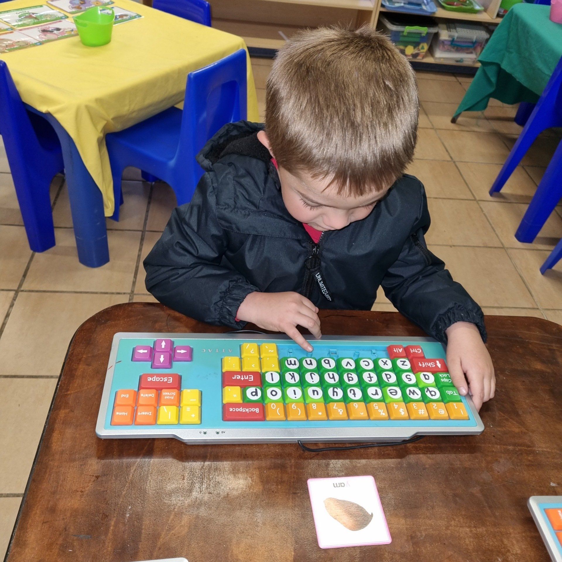 A young boy sits at a table playing with a keyboard