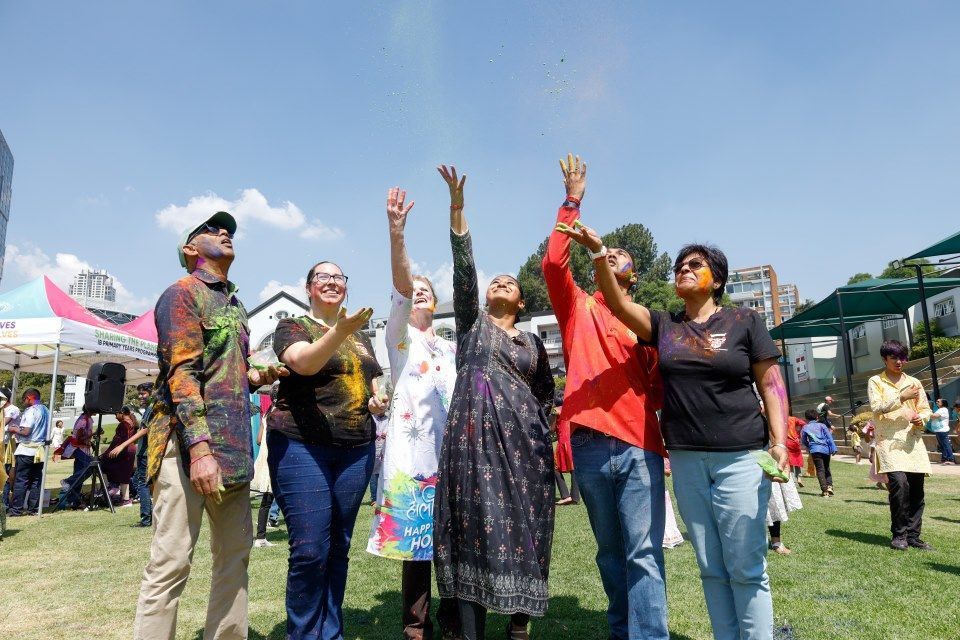 A group of people are standing in a park looking up at the sky.
