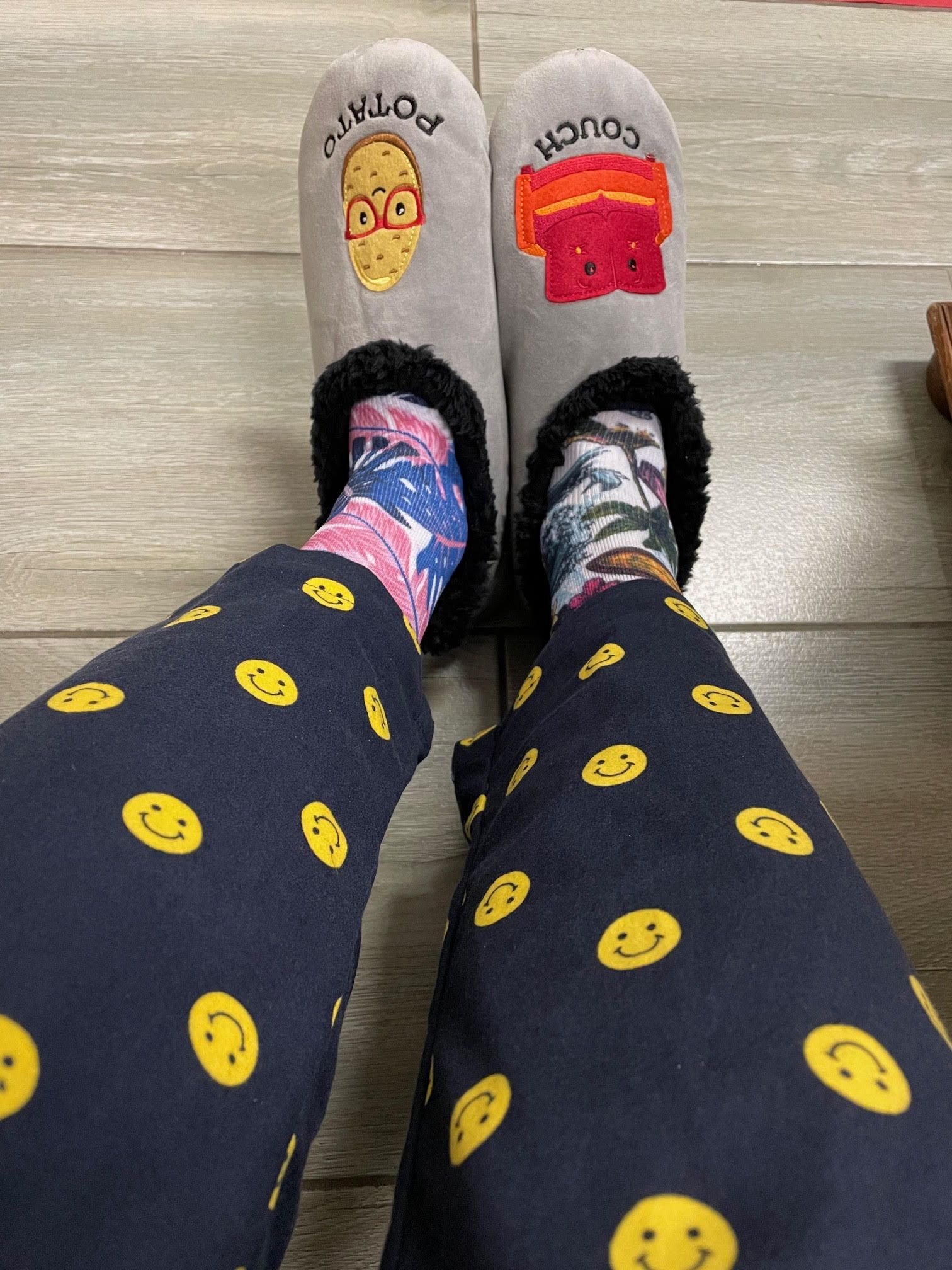 A person wearing slippers and polka dot pants with smiley faces on them.