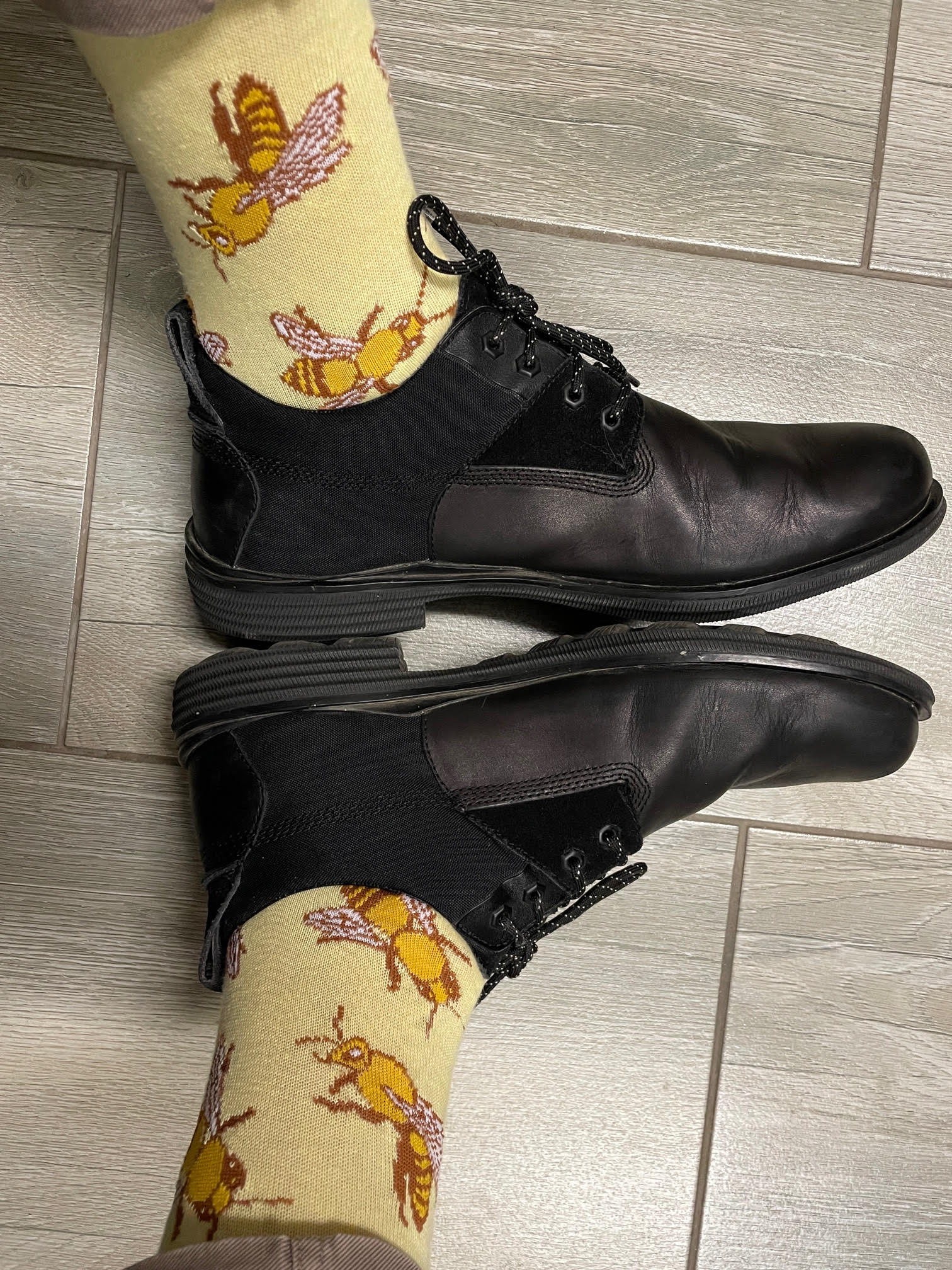 A person wearing black shoes and yellow socks with bees on them.