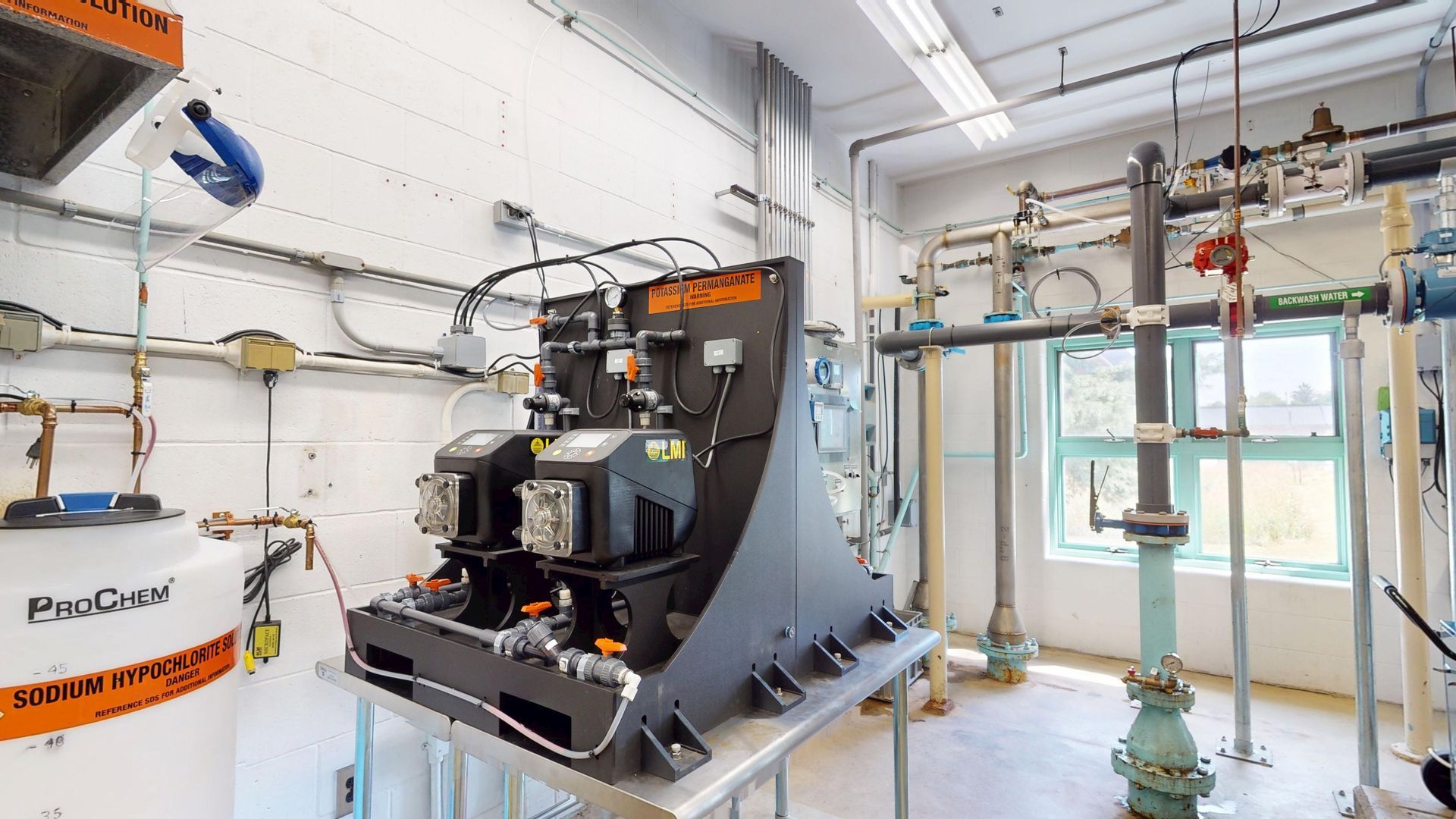 A water treatment facility with machinery, tanks, and pipes. The equipment is in an industrial setting with visible plumbing.