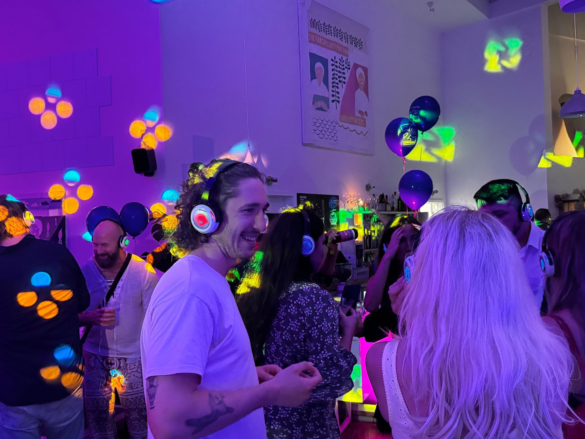 People wearing headphones at a silent disco, lit with neon colors.