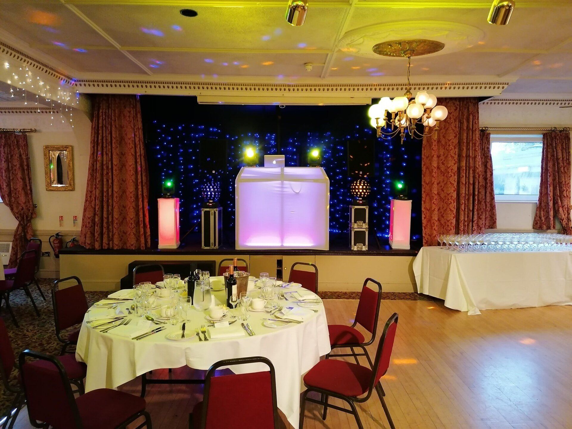 Banquet hall set up for an event with a stage and tables. Red and white decor.