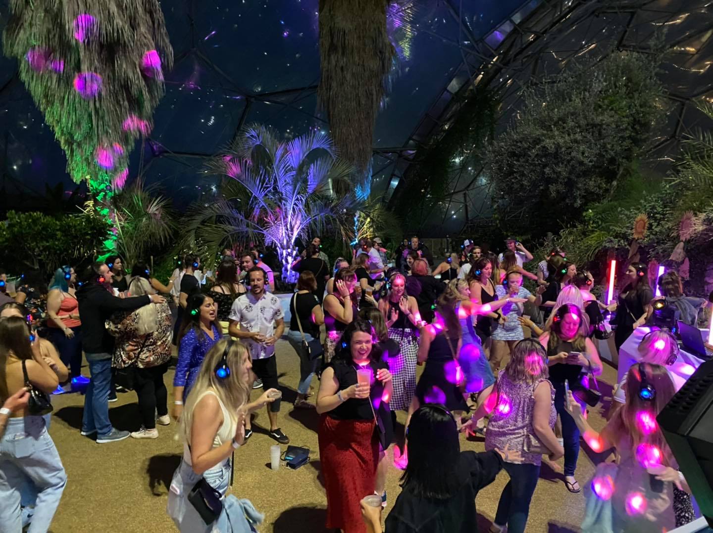 People dancing at a silent disco under colorful lights.