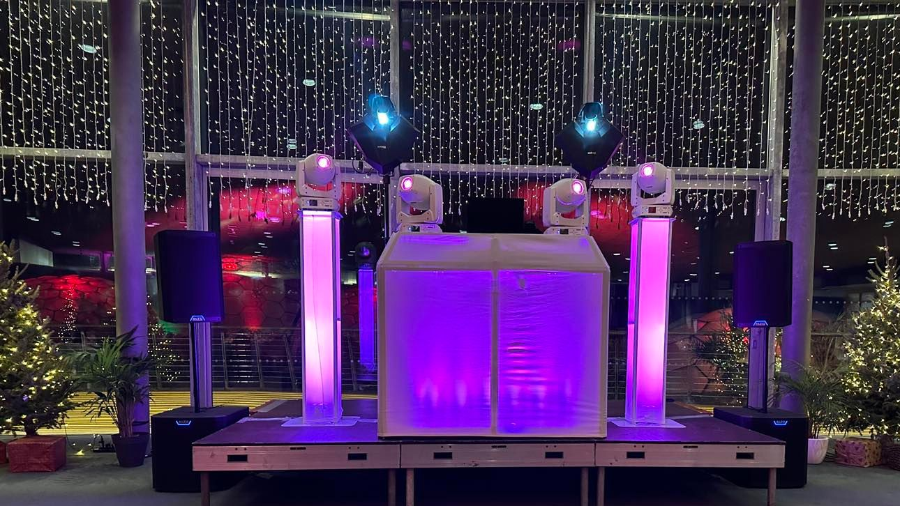 DJ setup with red and white lighting in a stone arched venue.