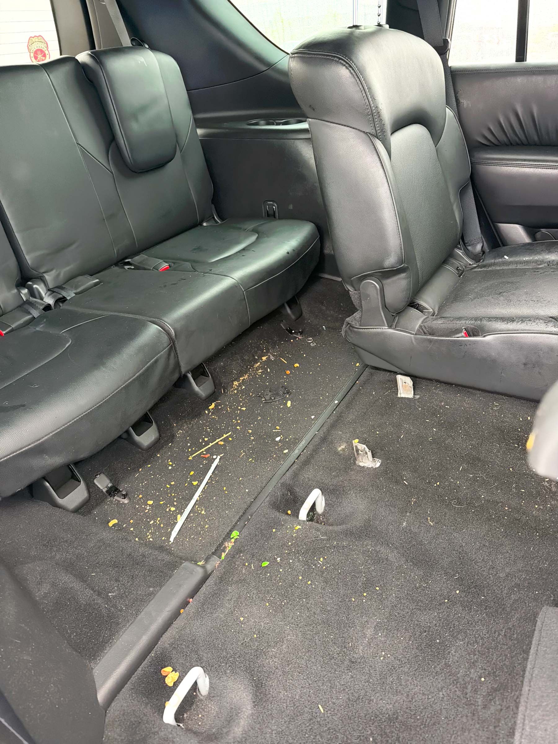 Car interior with black seats and debris scattered across the floor.