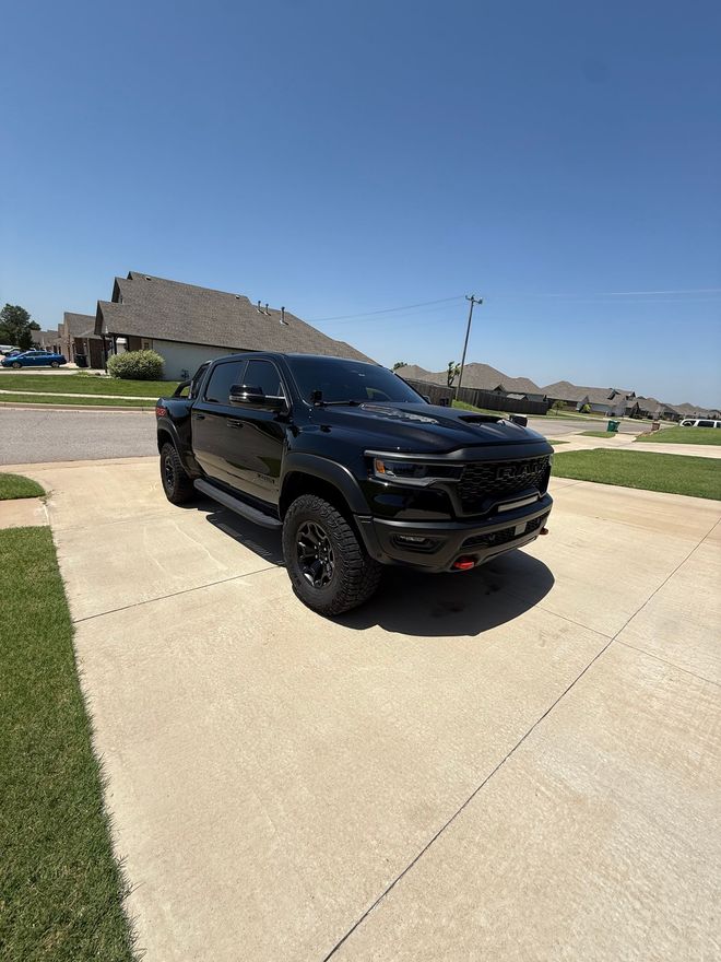 Black SUV parked on a driveway under a clear blue sky in a suburban neighborhood.