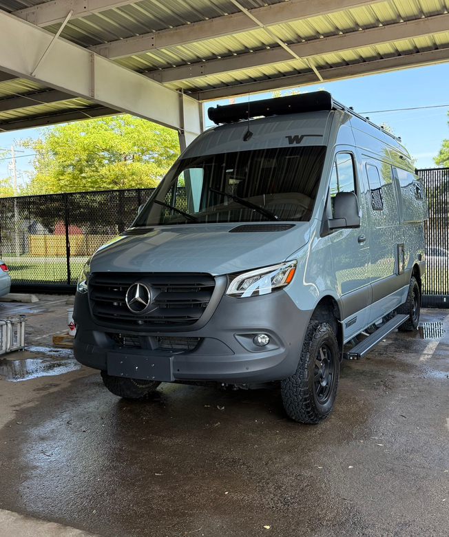 Black SUV covered in soap suds being washed in a car wash