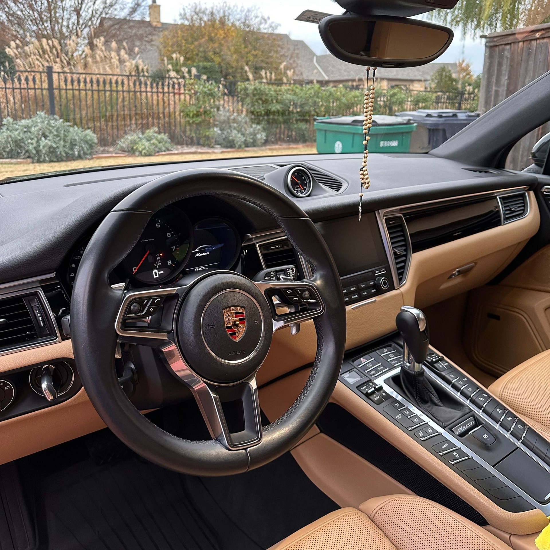 Porsche interior with tan leather seats, black steering wheel, and dashboard view from the driver’s seat.