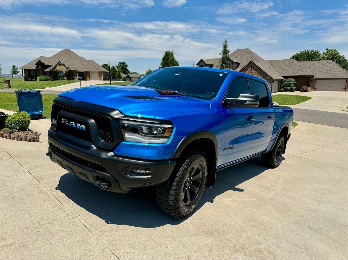 Blue pickup truck parked in a suburban driveway on a sunny day