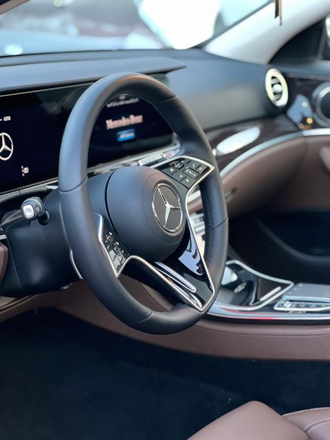 Mercedes-Benz car interior with black leather steering wheel and dashboard, close-up view