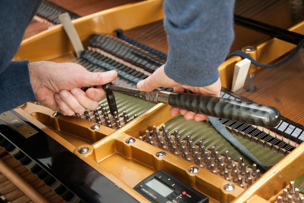A Man in An Apron Is Working on A Piano — David Simpson Pty Ltd in Mareeba, QLD