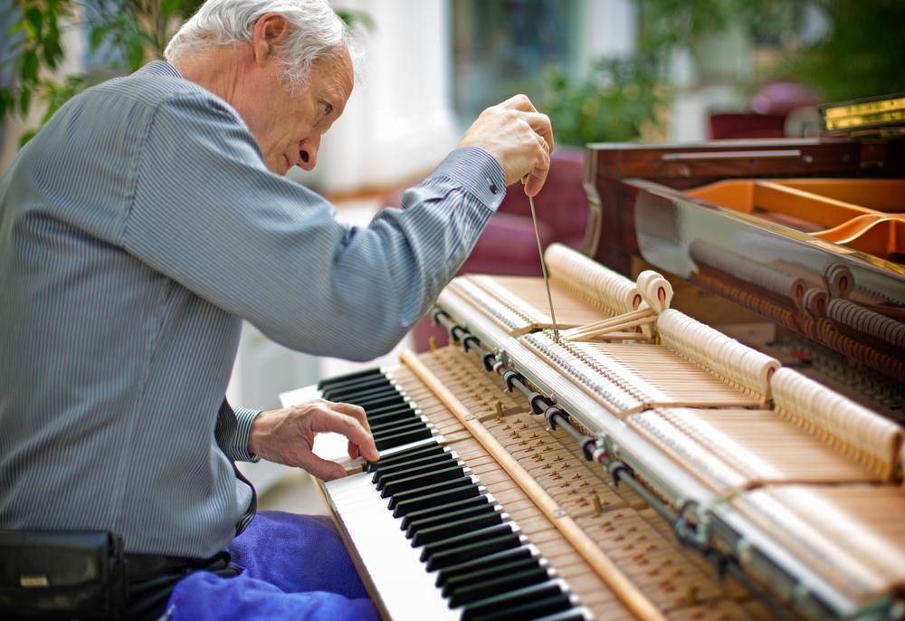 A Man Is Working on A Piano with A Pair of Tweezers — David Simpson Pty Ltd in Atherton, QLD