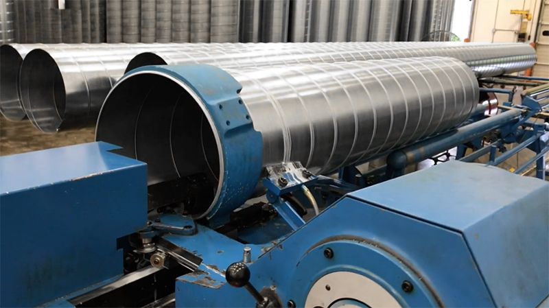 A machine is cutting a metal pipe in a factory.