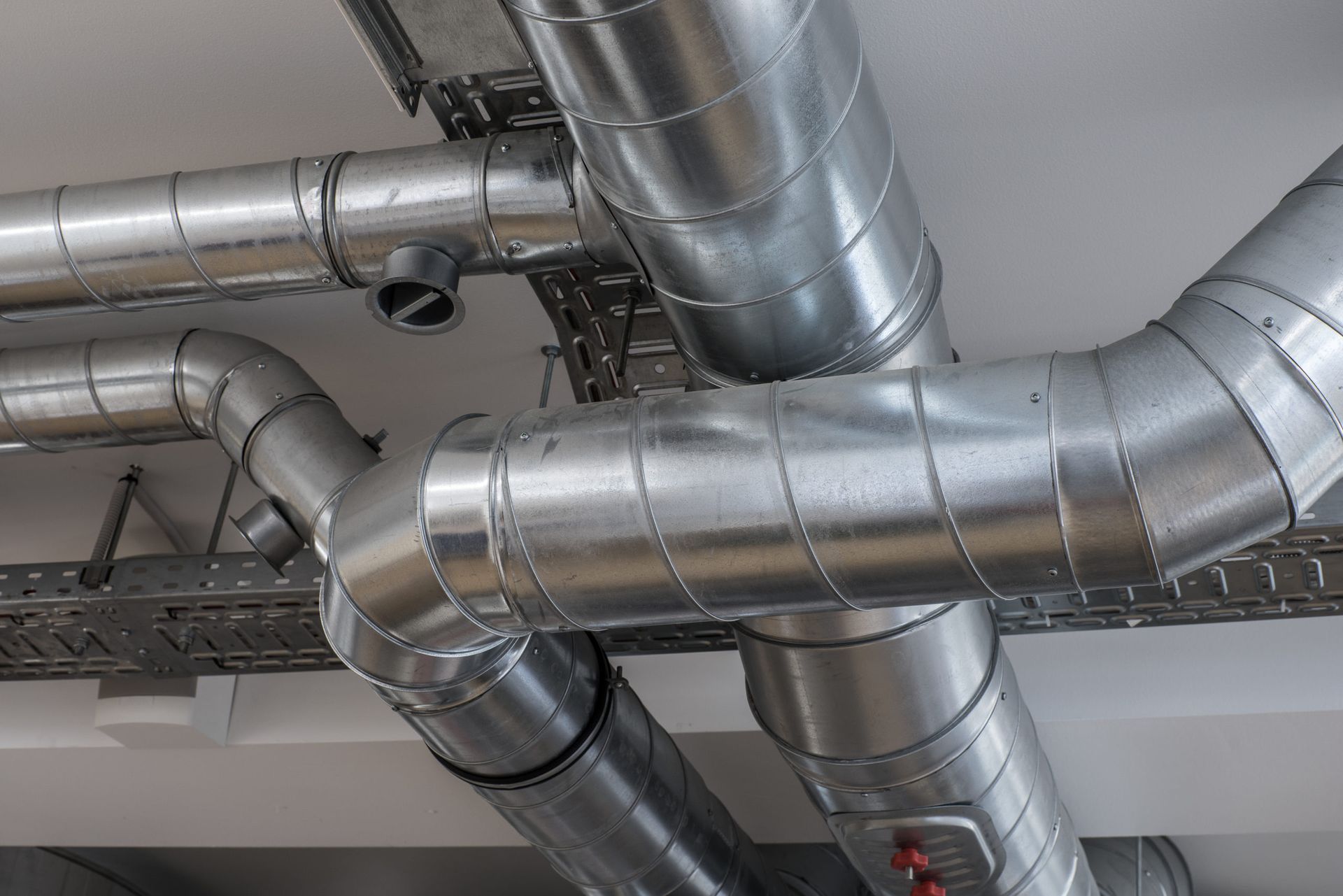 A bunch of metal pipes are hanging from the ceiling of a building.