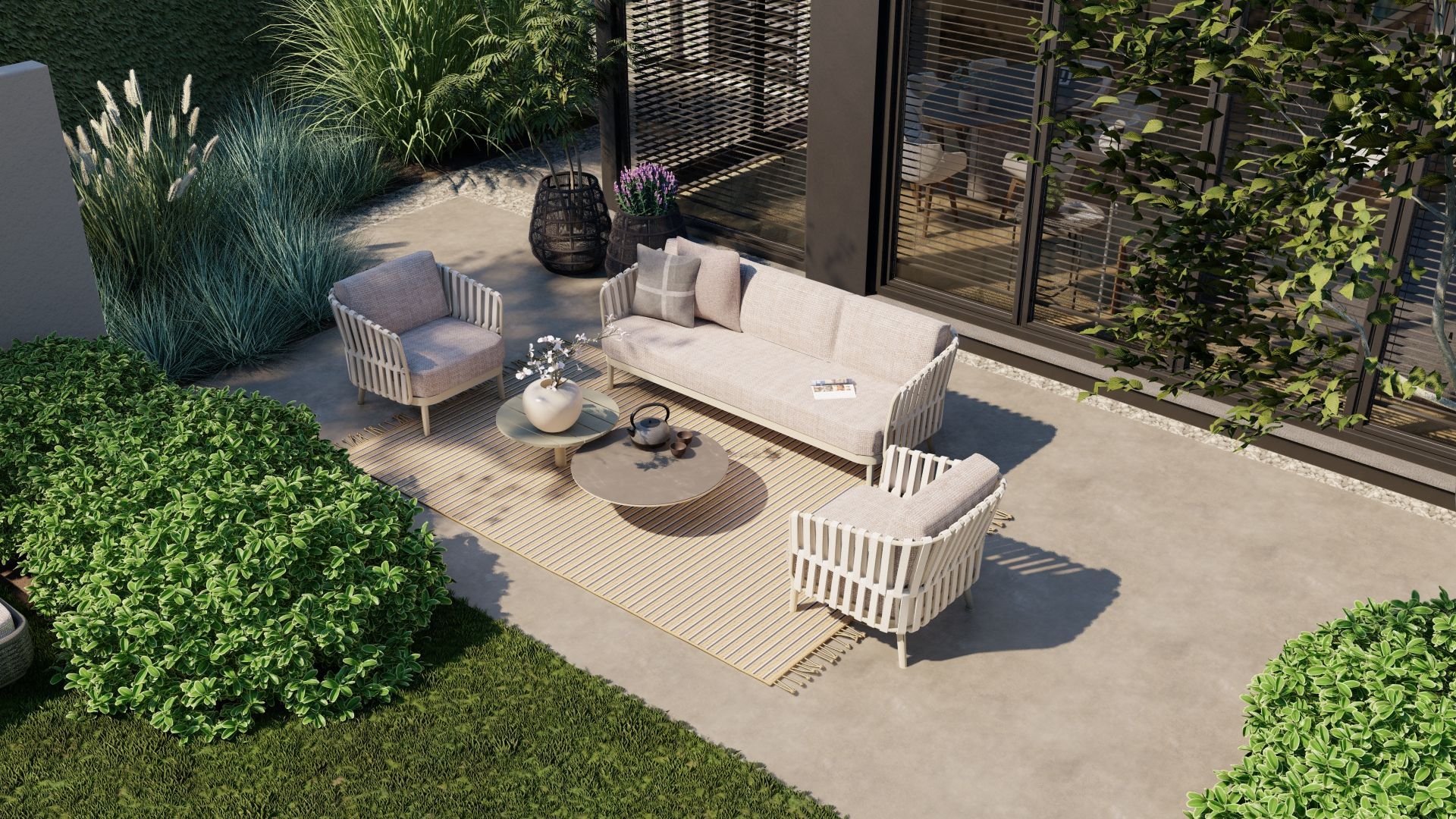 Terras met beige bank, stoelen en salontafel op een vloerkleed. Groene planten en een modern gebouw op de achtergrond.