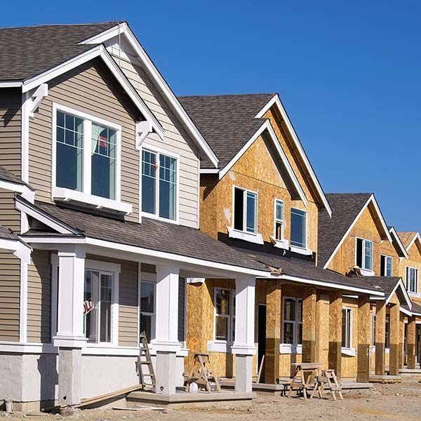 Row of new suburban houses with white trim, gray roofs, and a bright blue sky