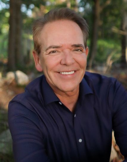 A man in a blue shirt is smiling for the camera.