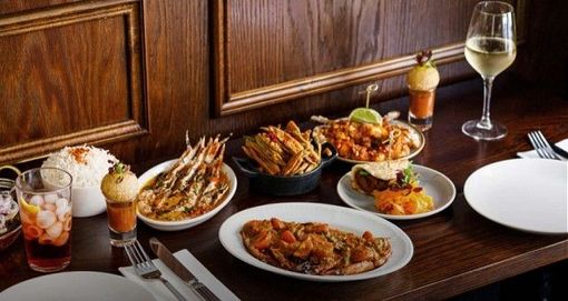 A table set with a variety of gourmet dishes, including shrimp, rice, appetizers