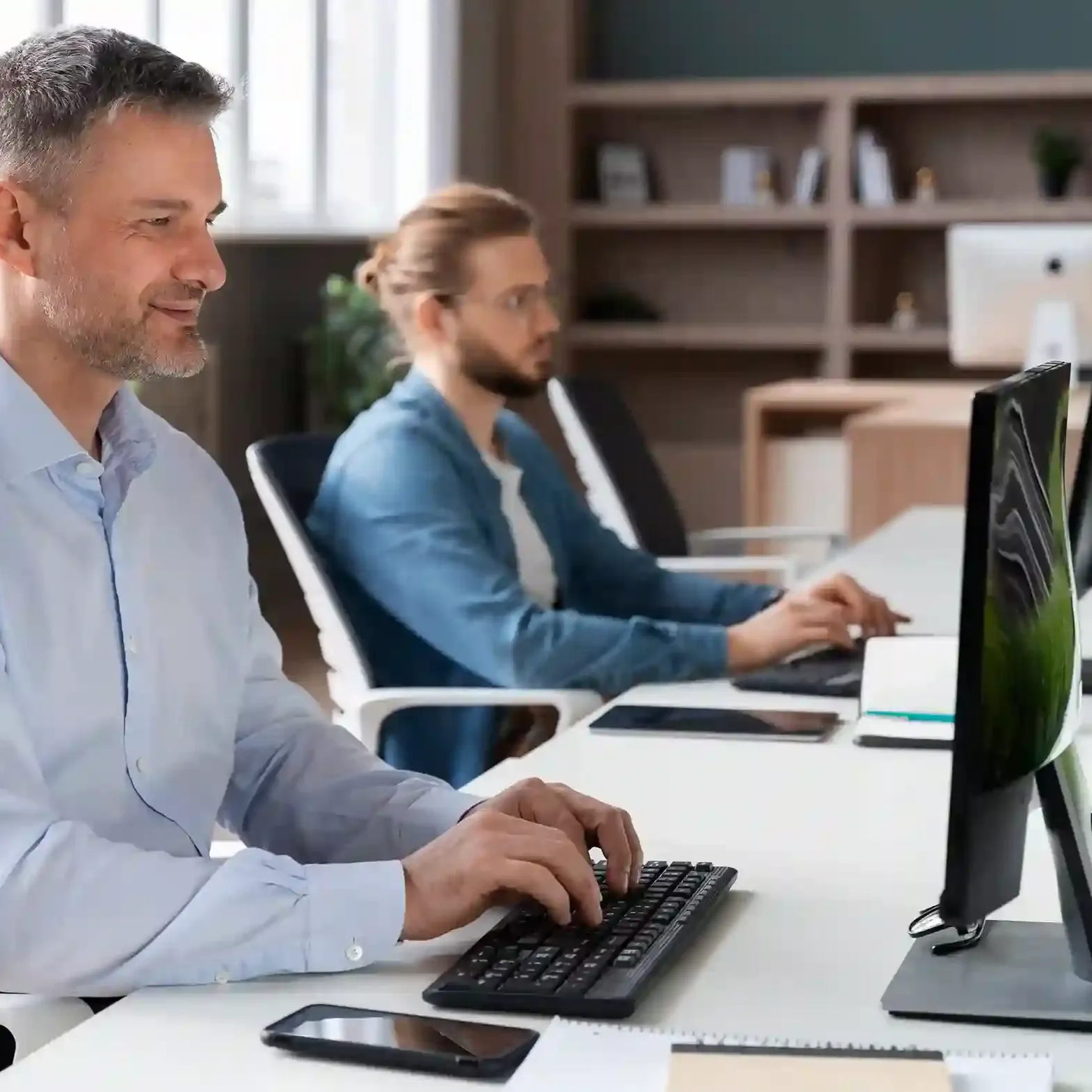 Two people in a bright office working at their computers.
