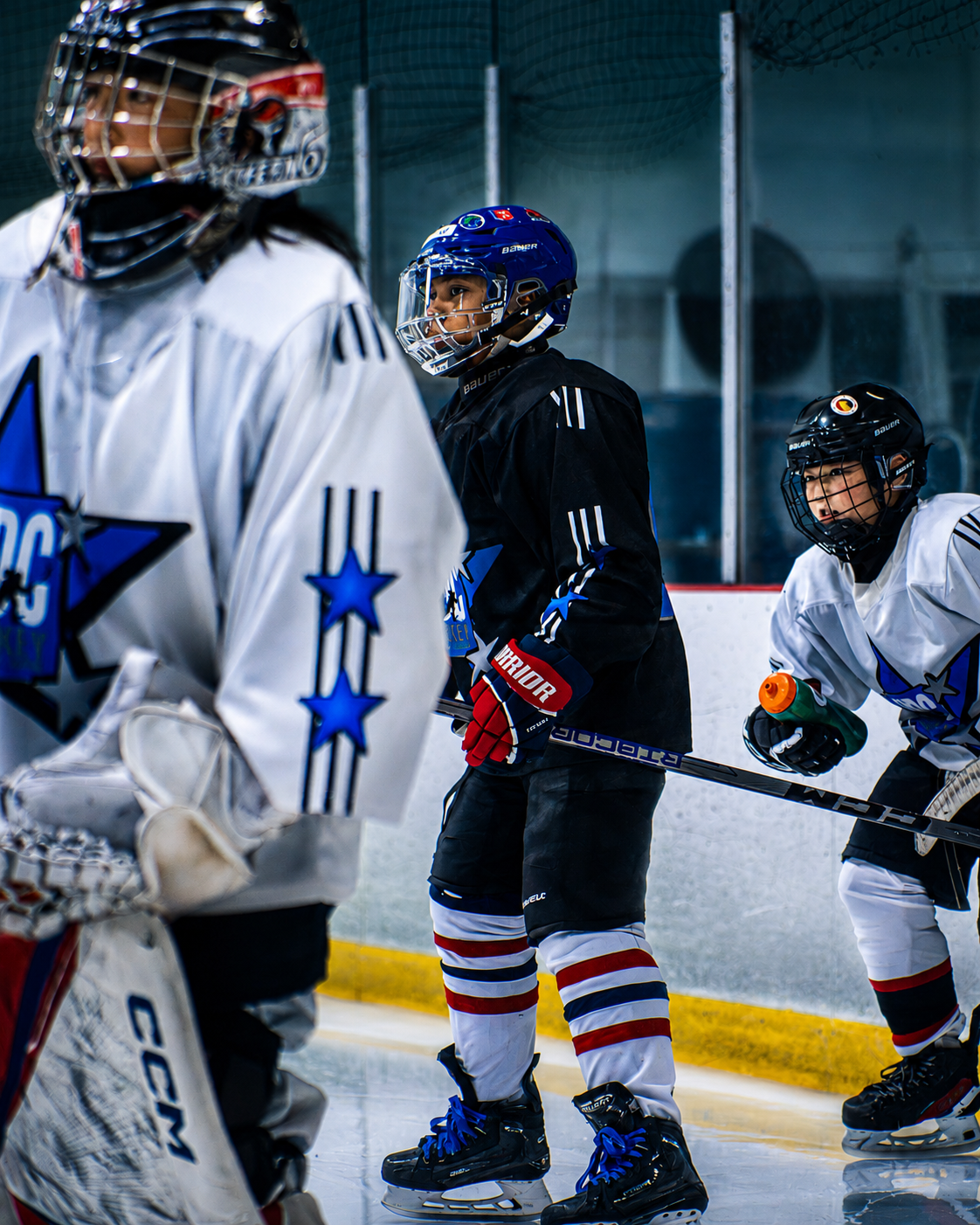 Youth hockey players in white and black jerseys on ice, skating during a game.