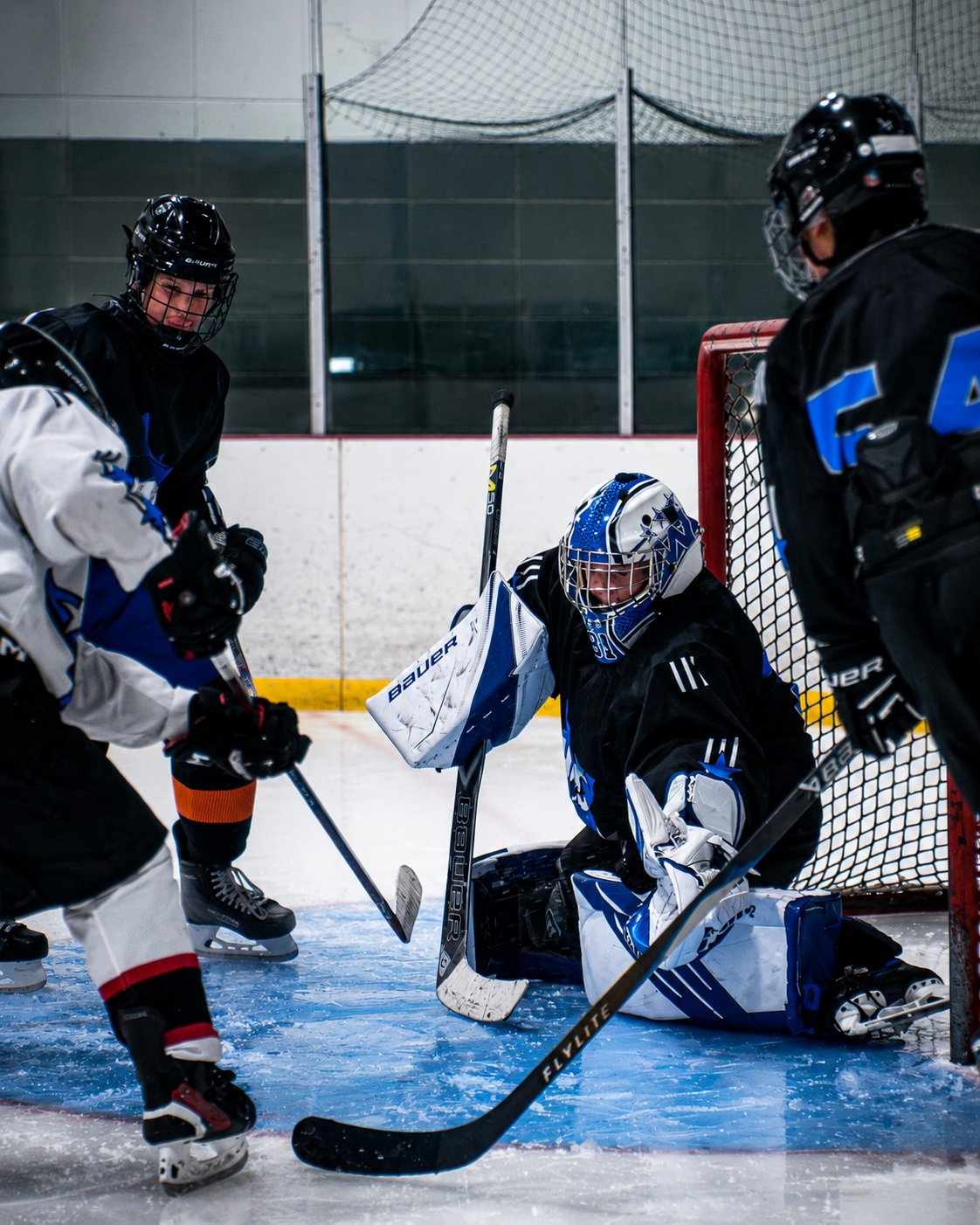 Ice hockey game with a goalie blocking a shot near the net during a close play