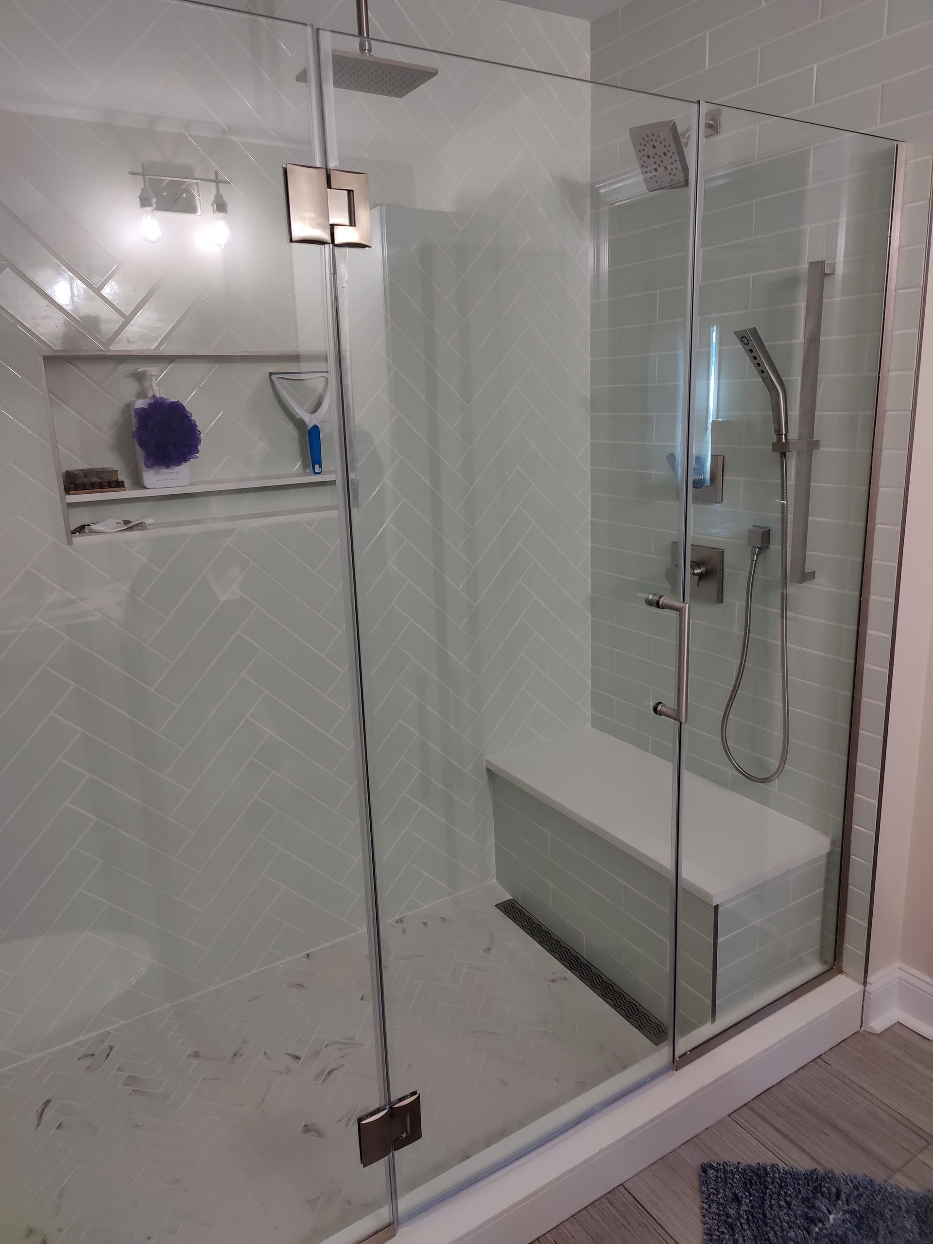 Glass shower enclosure with white tiled bathroom and built-in bench seat