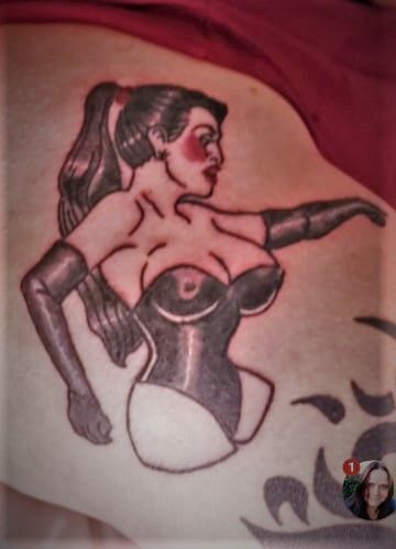 Tattoo of a woman in a corset, with a ponytail, reaching forward with one arm.