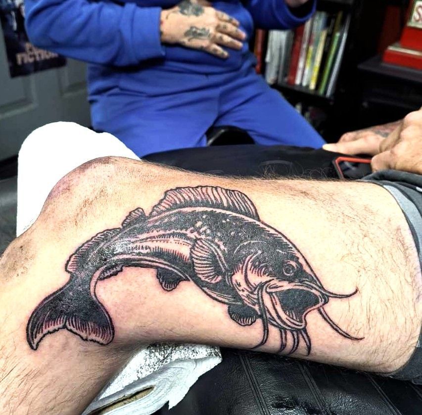 Black and gray catfish tattoo on a person's leg, in progress.