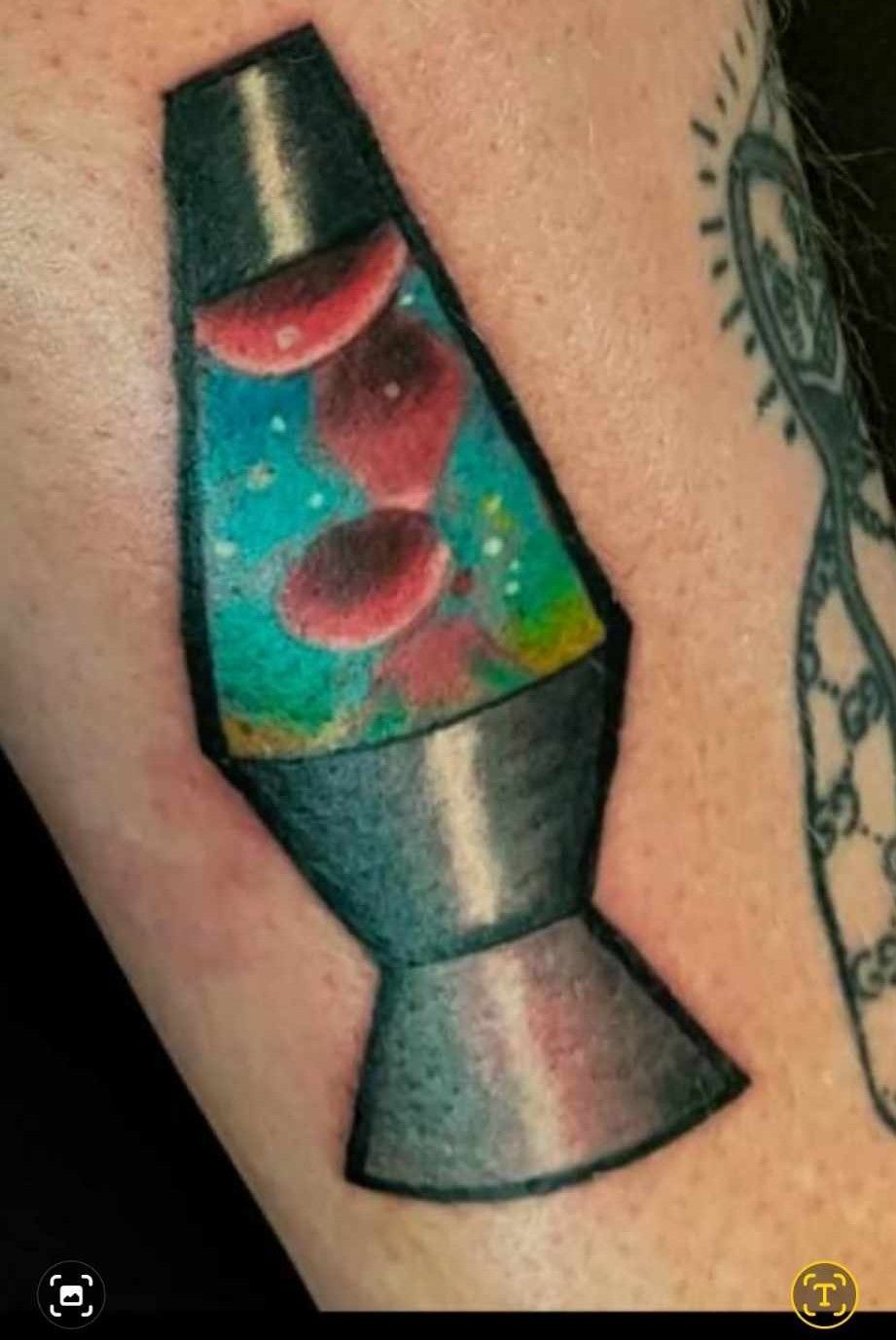 Tattoo of a lava lamp with red blobs against a colorful background, gray base. Tattoo on skin.