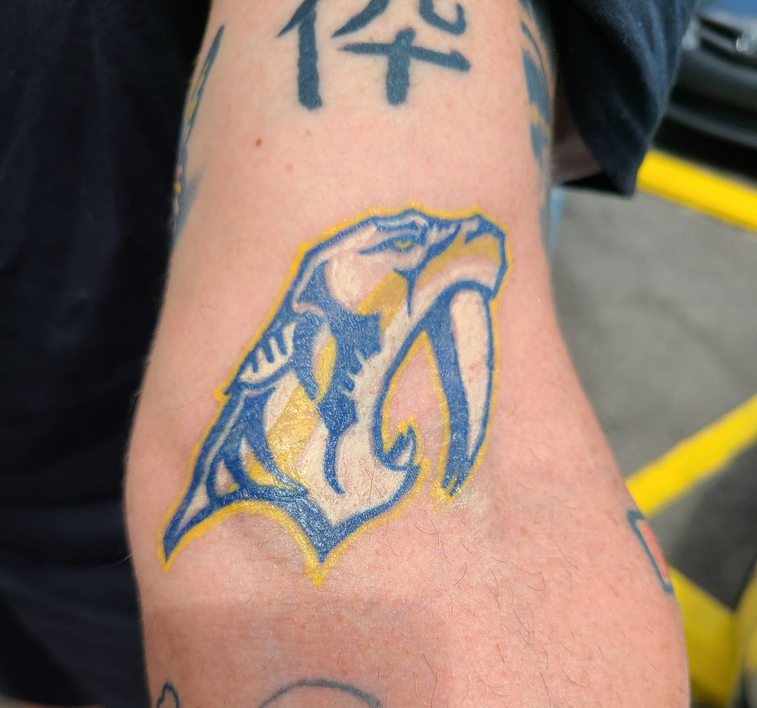 Nashville Predators logo tattoo on an arm, blue and gold colors.