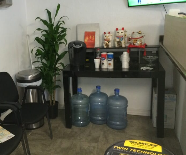 Office corner: water bottles, coffee station with plants, trash can, chairs, and Lucky Cat figurines | Mike's Automotive AC