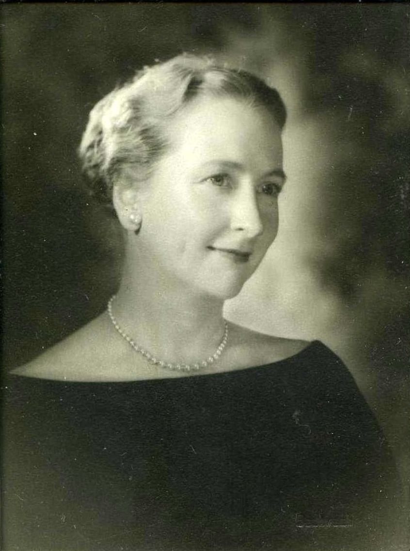 Black-and-white portrait of a woman in an off-the-shoulder dress and necklace, looking slightly to the side.