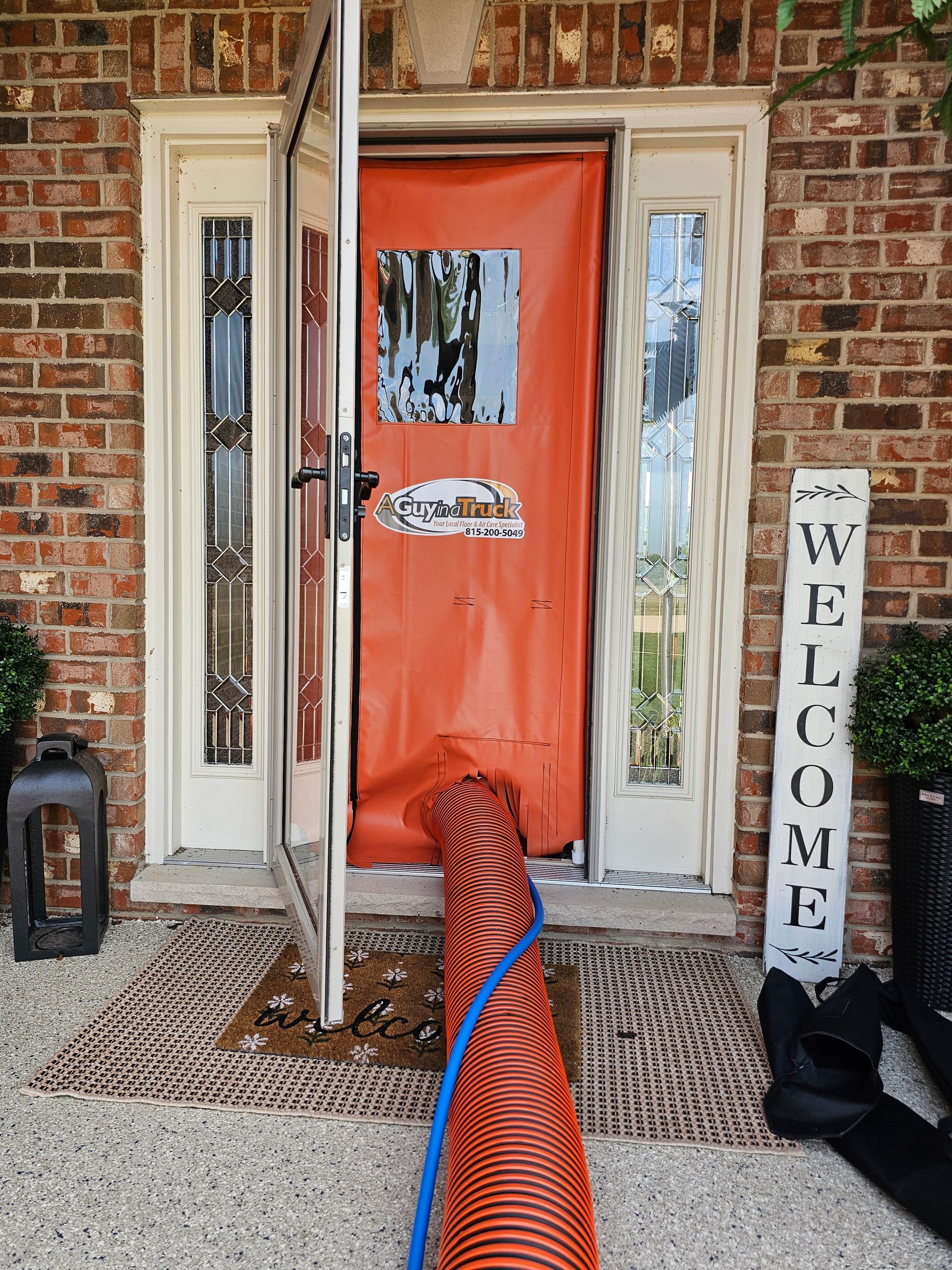 Orange containment door with A Guy in a Truck logo set up for residential air duct cleaning service.