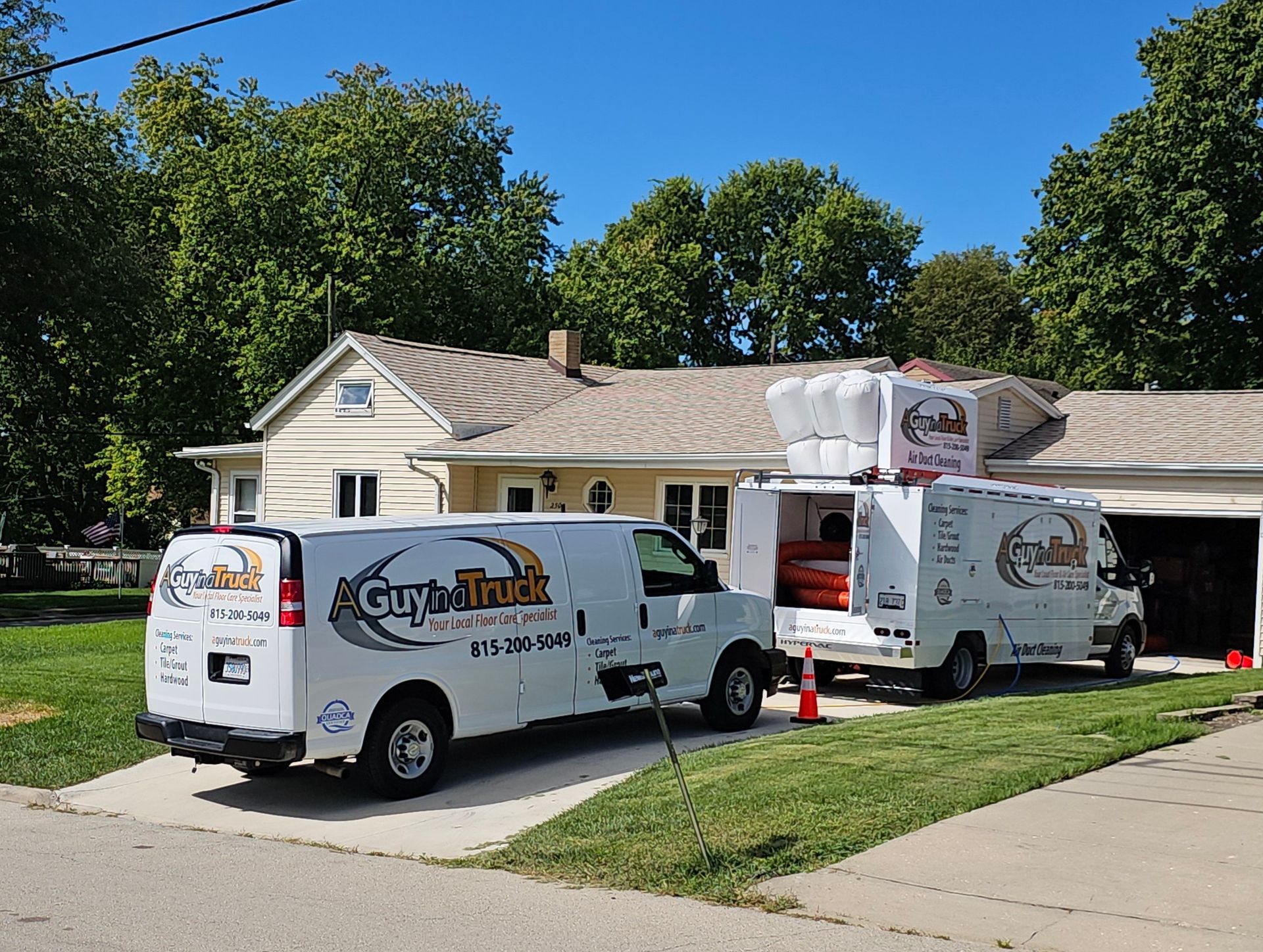 A Guy in a Truck service vans parked at a residential home for professional air duct cleaning.