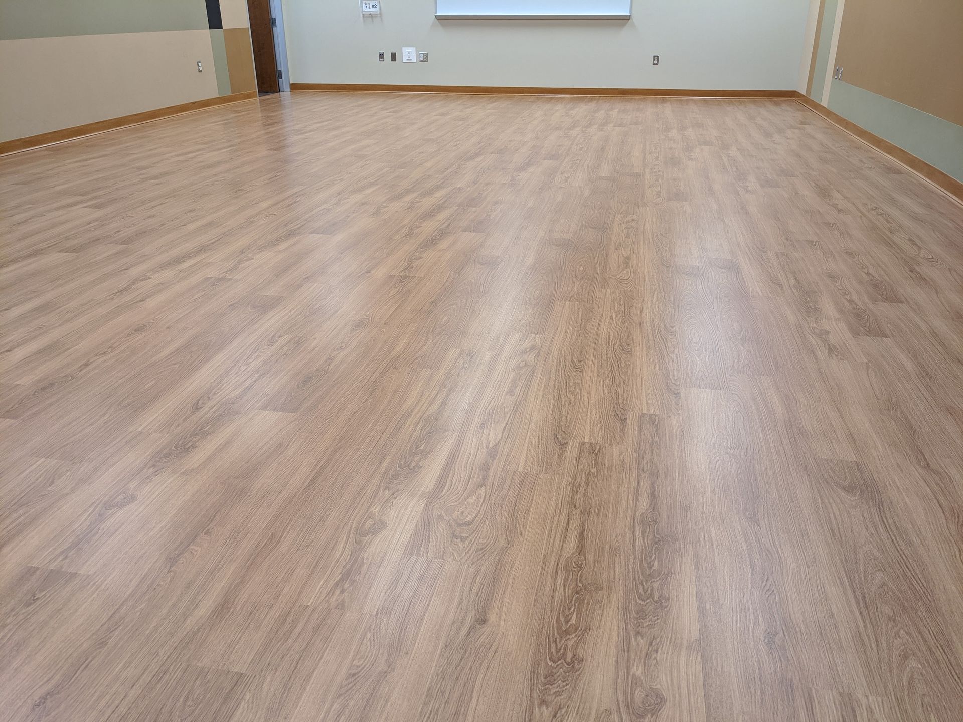 Wide view of freshly cleaned commercial vinyl plank flooring, showing even finish and natural wood look