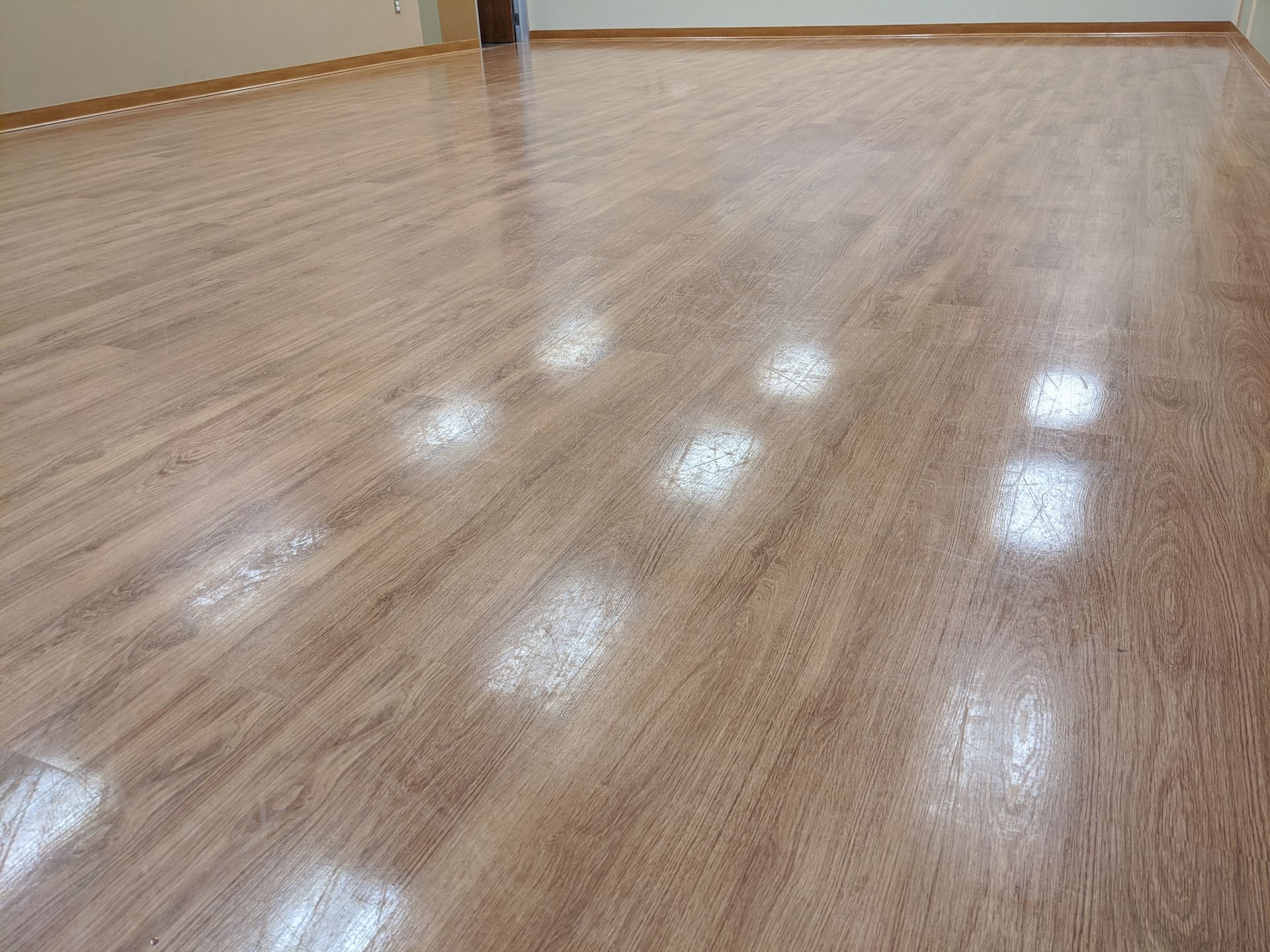 Before commercial vinyl plank floor cleaning, showing dull finish and visible wear across open room space