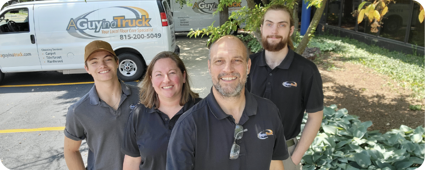 A Guy in a Truck team smiling outdoors in front of their service vans.