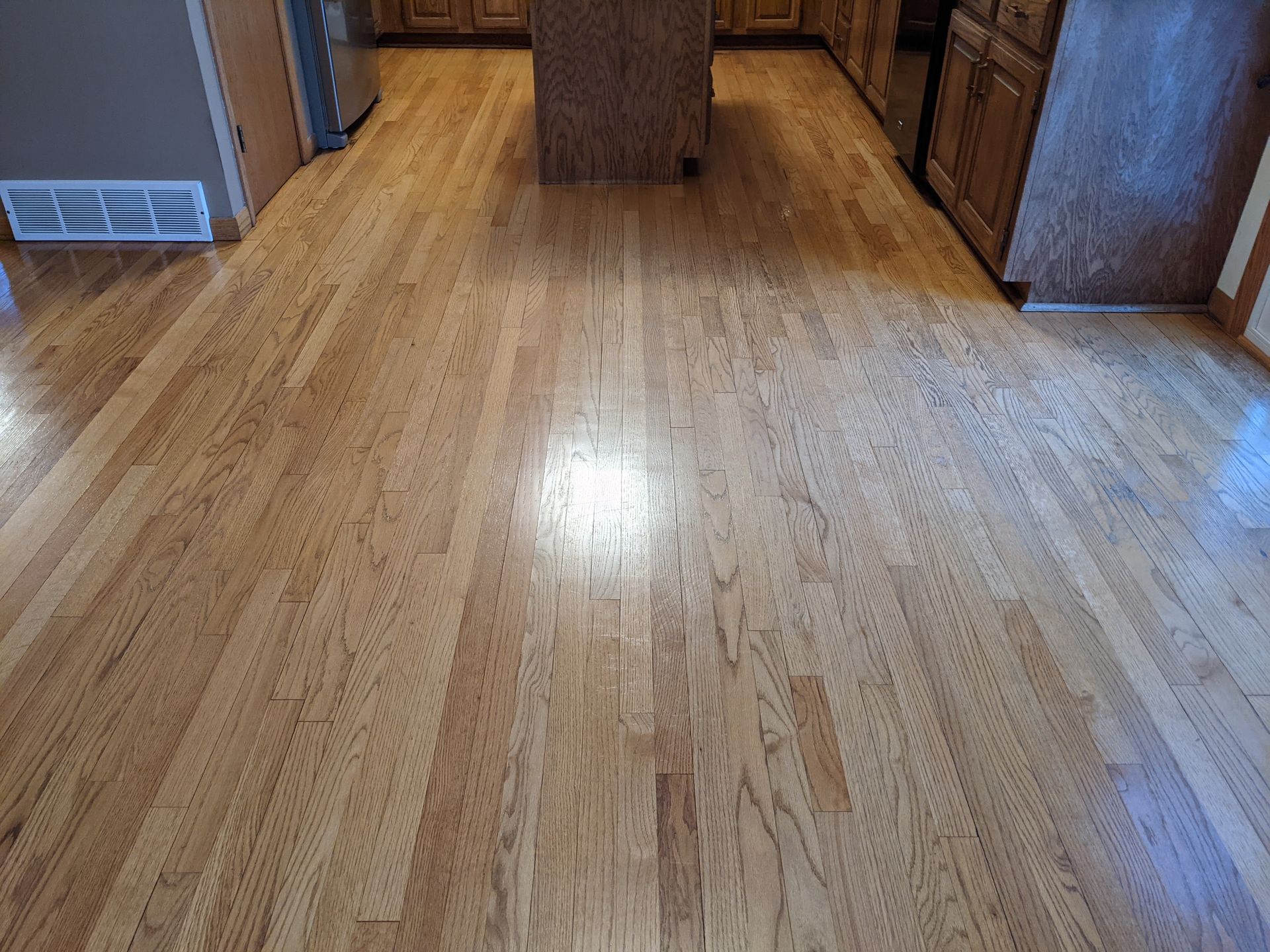 Hardwood kitchen floor after professional cleaning with restored shine and more even appearance