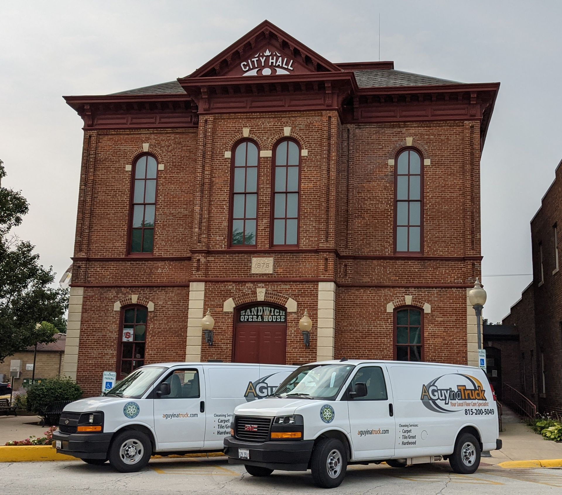 Two A Guy in a Truck service vans parked in front of a historic downtown building during commercial cleaning work