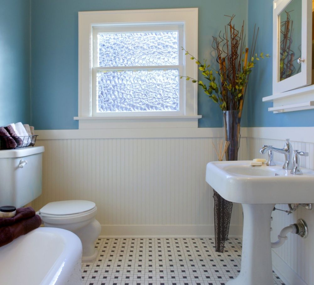 Bright blue bathroom with pedestal sink, mosaic tile floor, frosted window, and classic fixtures