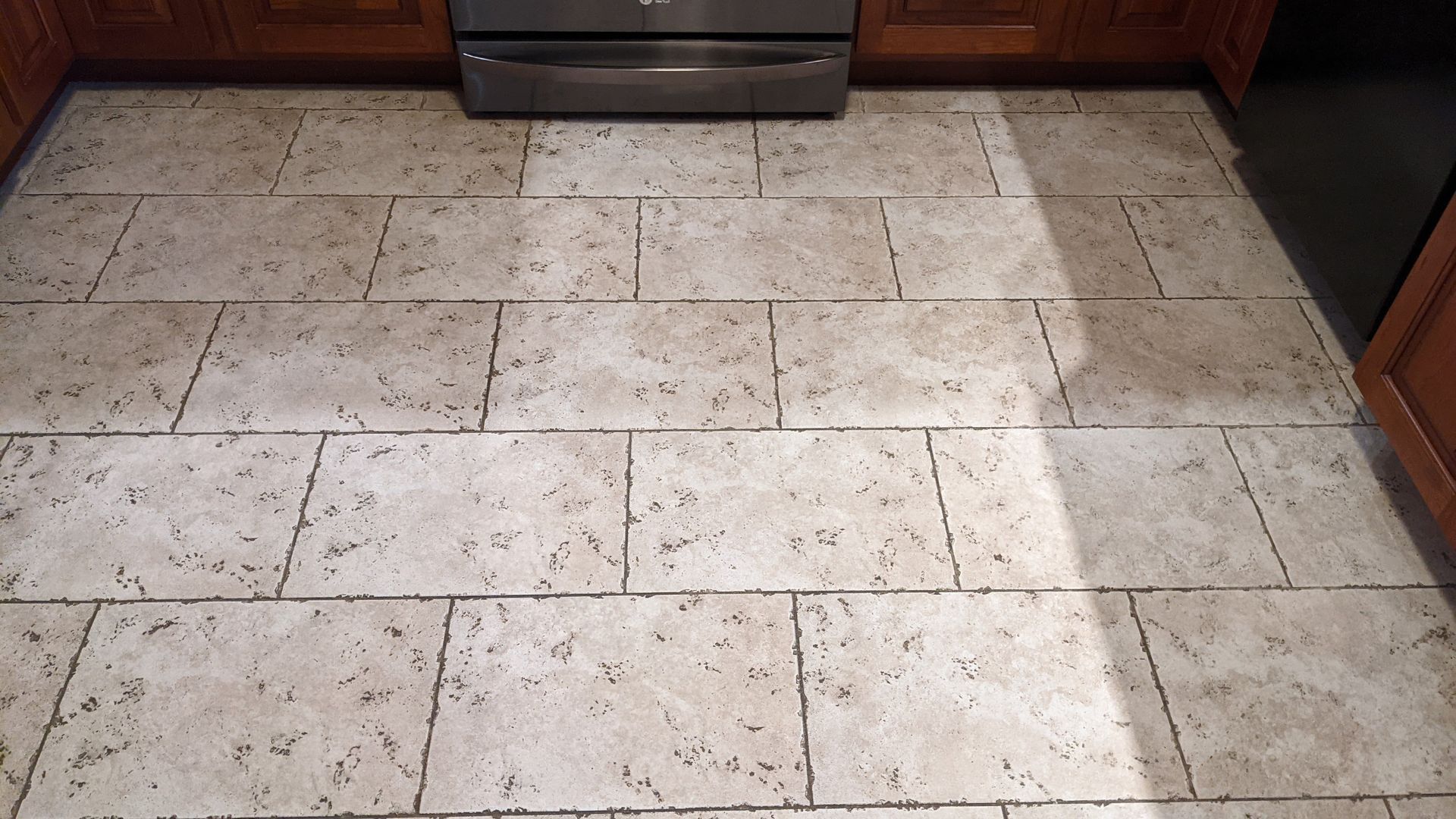 Kitchen tile floor before professional tile and grout cleaning with spotted tiles and dark grout lines