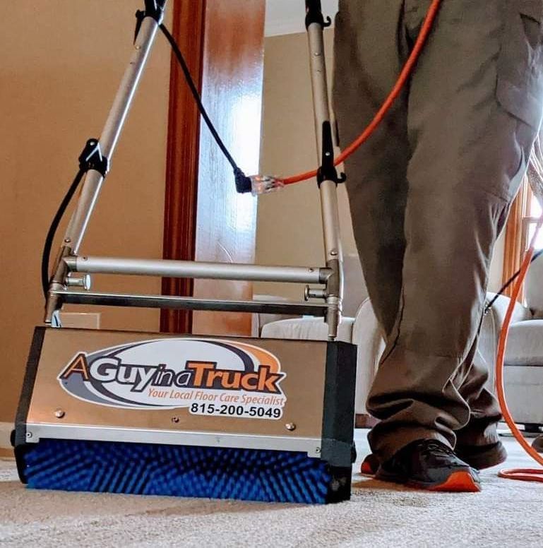 A person using a carpet cleaning machine with a logo that reads 