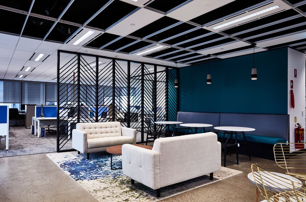 Clean modern office lounge with upholstered seating, area rug, and open workspace after professional commercial cleaning
