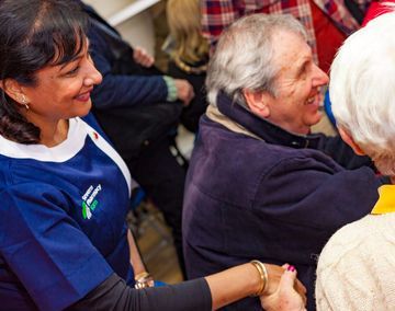 A woman is holding the hand of an older man in a group of people.