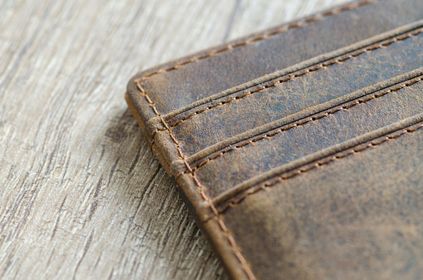 A close up of a brown leather wallet on a wooden table.