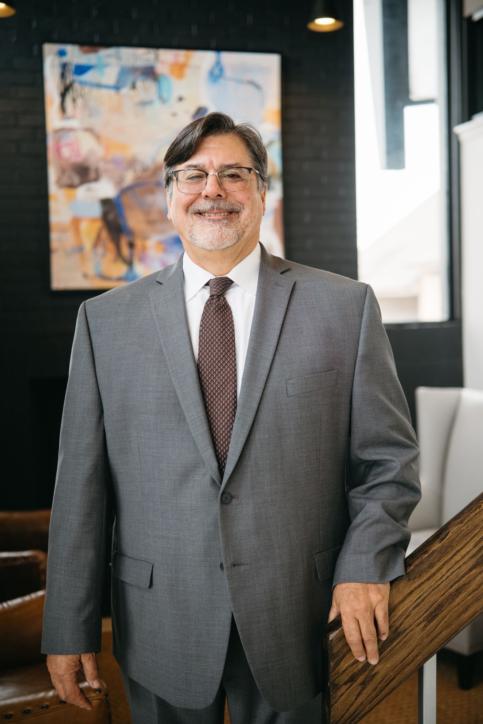 A smiling man wearing a gray suit.